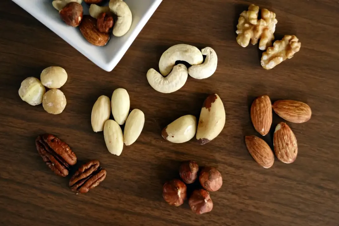 Selection of almonds, walnuts, cashews and pecans arranged on a wooden table