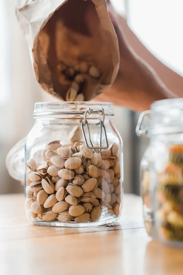 Nuts being poured into a glass storage jar